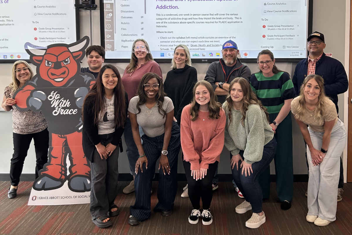 Group of students and instructors standing in front of a projector screen.