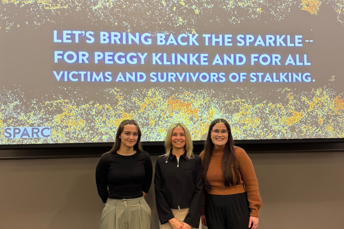 Emilie Whitehouse, Payton Miller, and Kim Retzlaff standing in front of the presentation slideshow.