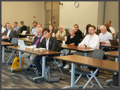 Group of people sitting at tables in a classroom.