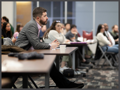 Man sitting at a table with group of other people.