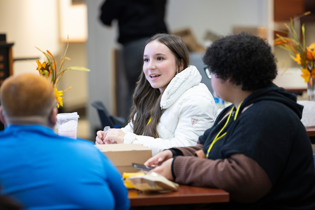 Three students sitting around a table talking.