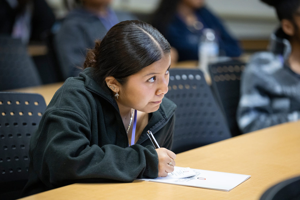 Student listening in a classroom taking notes.
