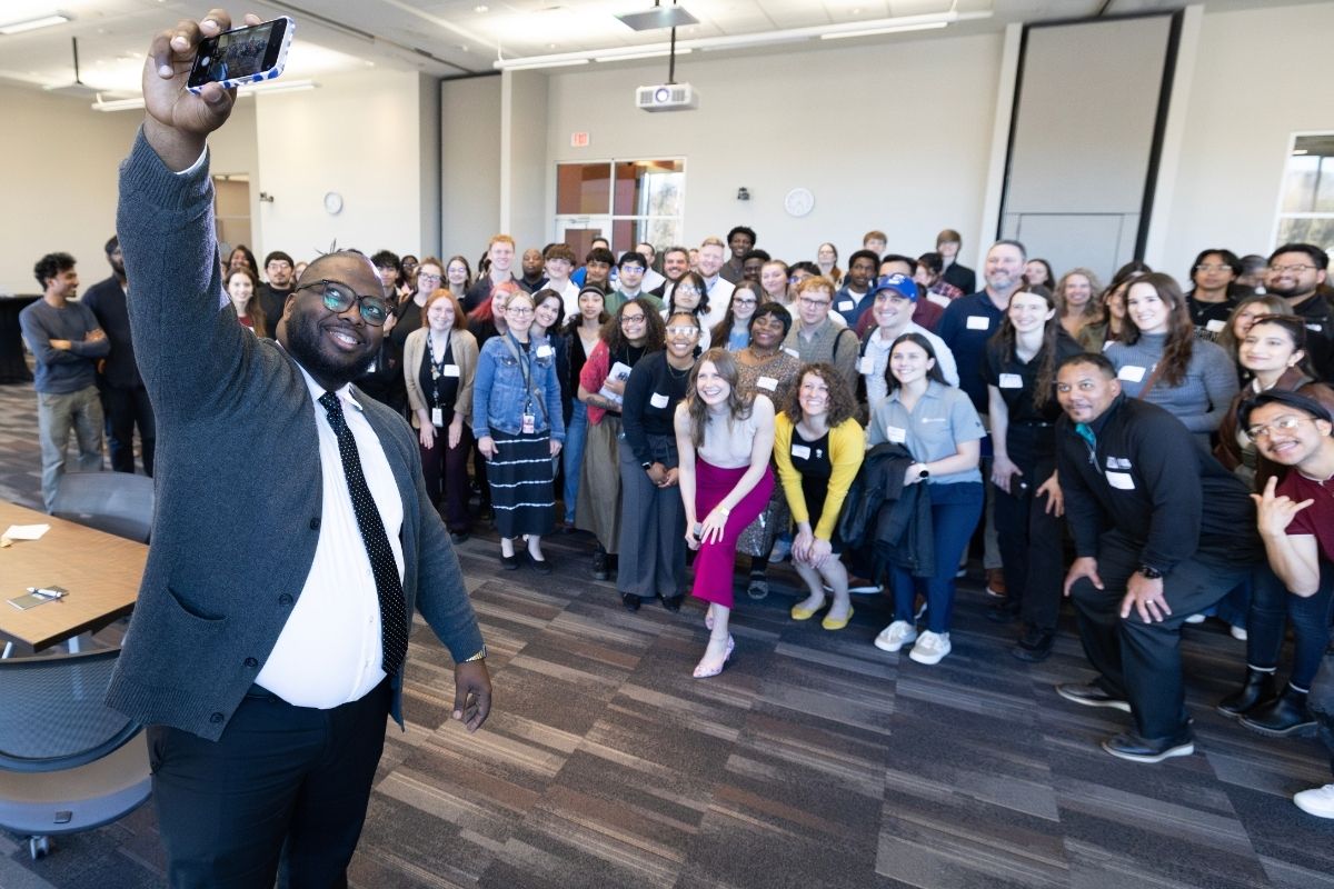 Image of a member of the Omaha Chamber taking a self portrait with a large group of UNO students. 