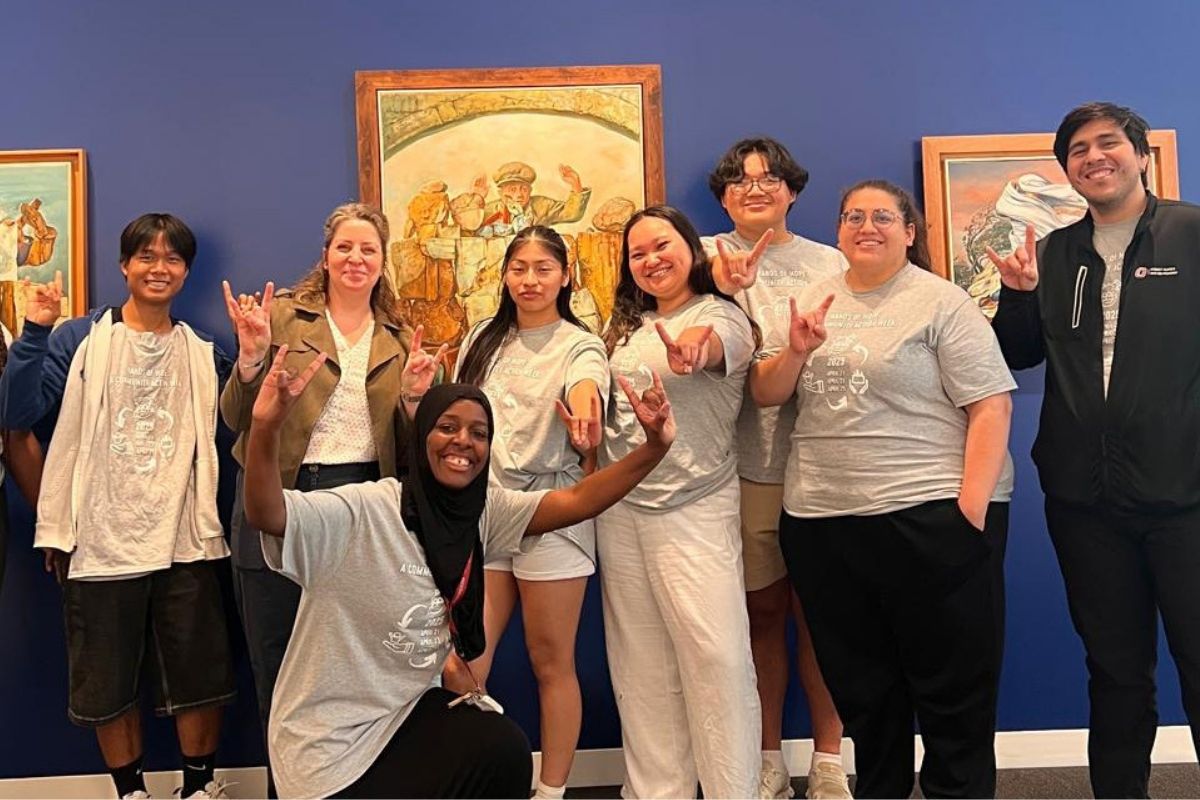 A group of UNO students and community participants pose together in front of artwork after completing a community-engaged learning project focused on art, culture, and connection.