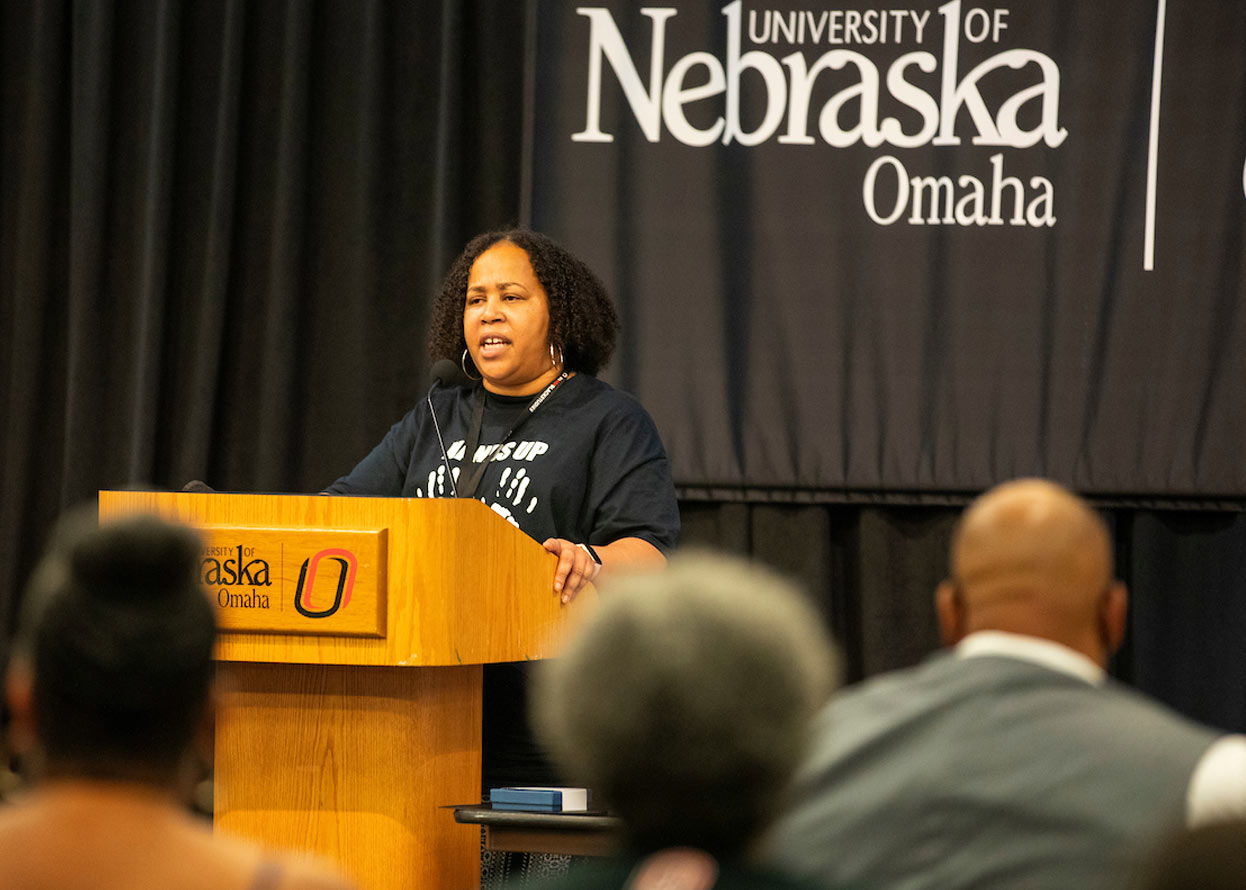  a woman standing at a podium, speaking to a crowd