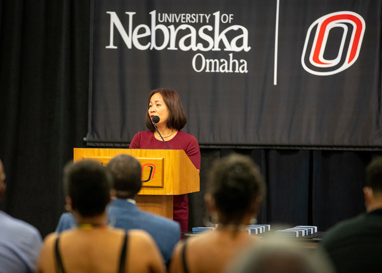  a woman standing at a podium, speaking to a crowd