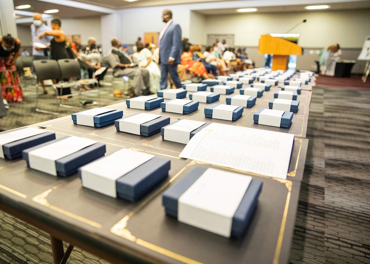 blue square gift boxes lined up on a table, with a crowd of people in the background