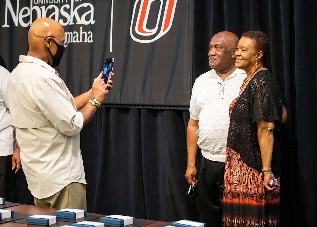 a man taking a photo of a woman and man standing together, all members of the omaha 54