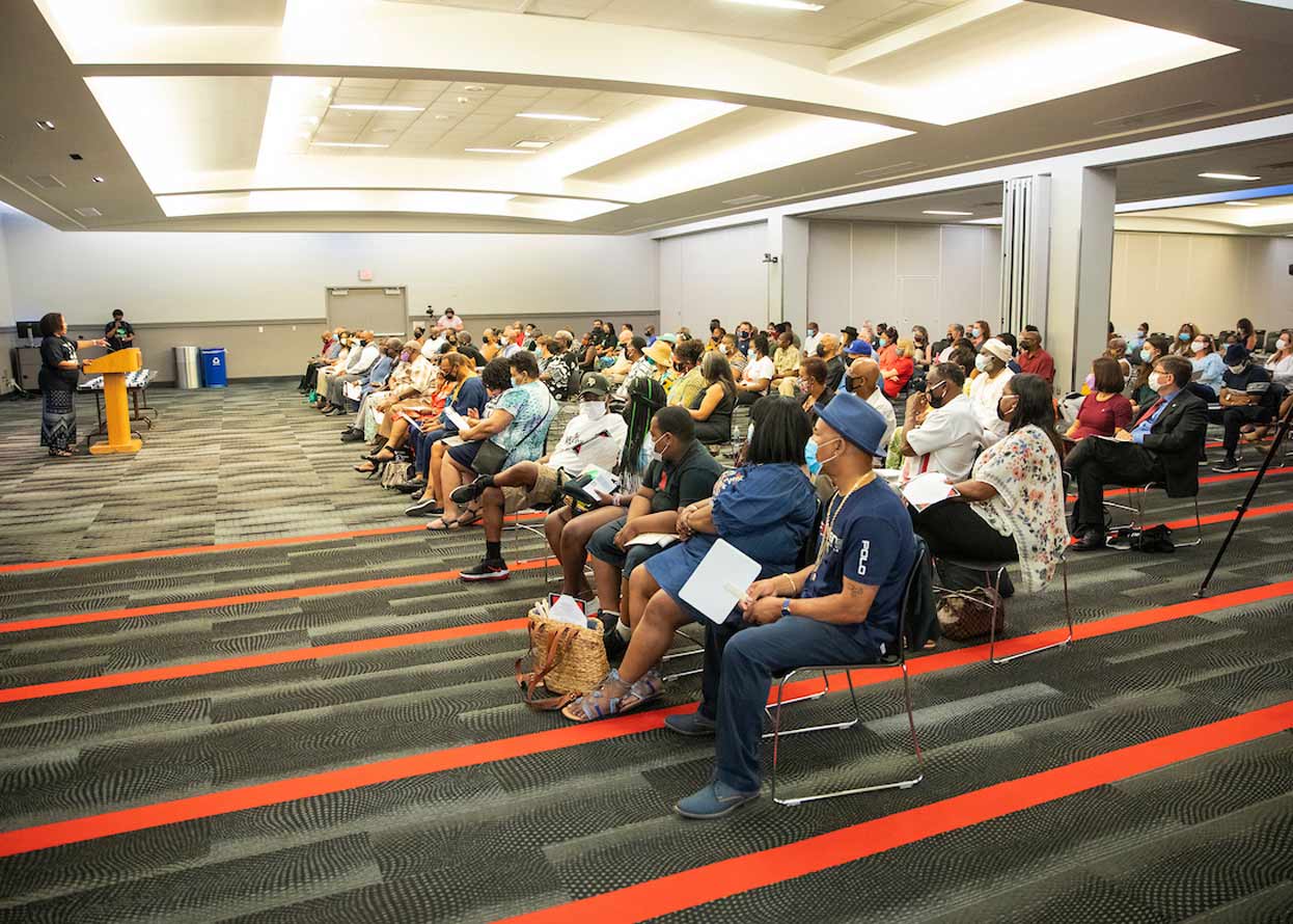 crowd of people listening to a speaker at a podium 