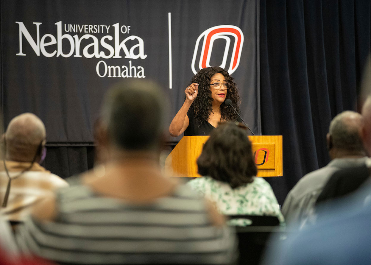 woman standing at a podium speaking to a crowd 