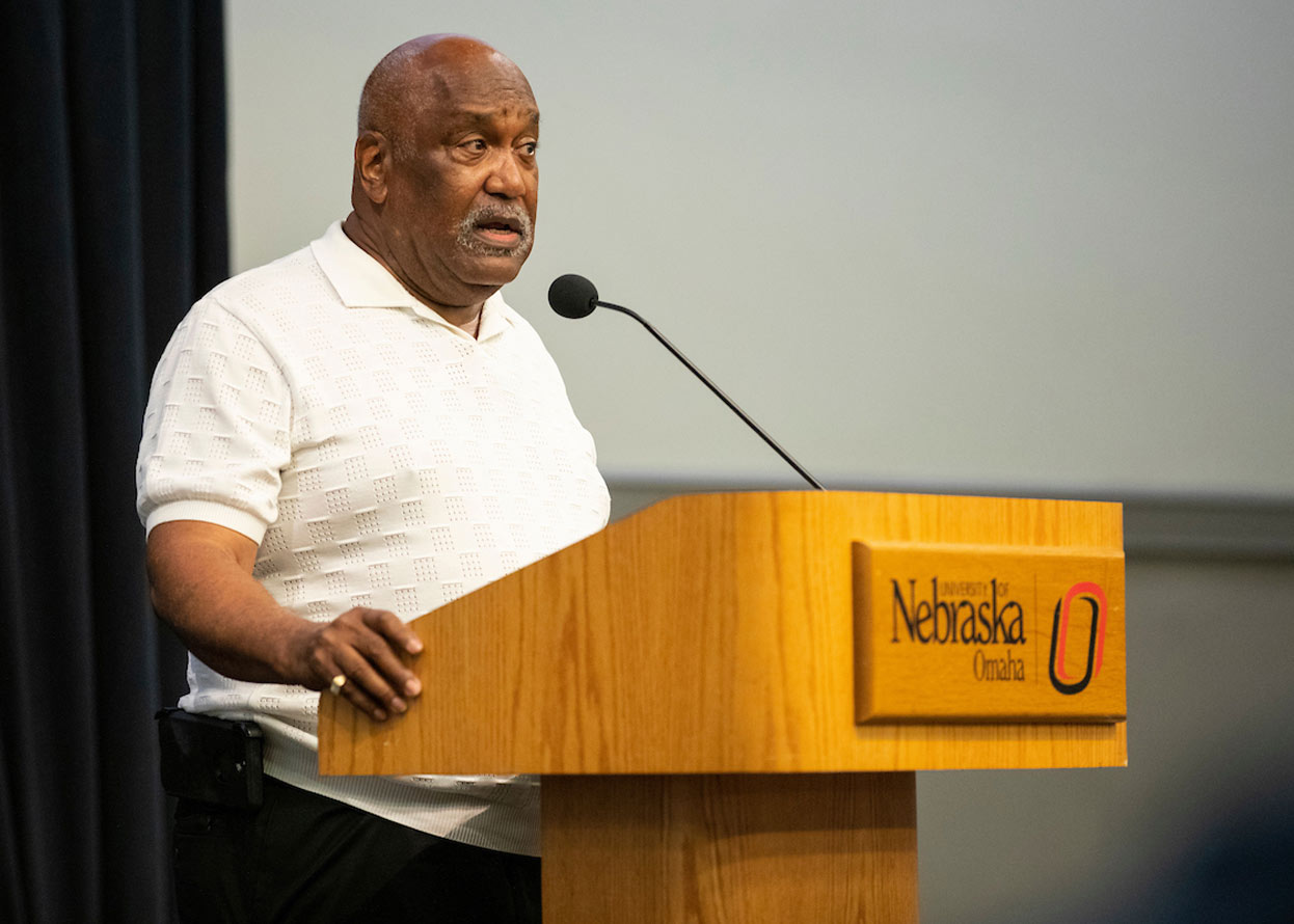 man standing a podium speaking to a crowd 