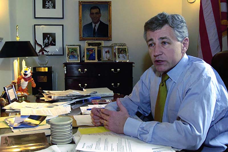 U.S. Senator Chuck Hagel talking while seated at office desk. 