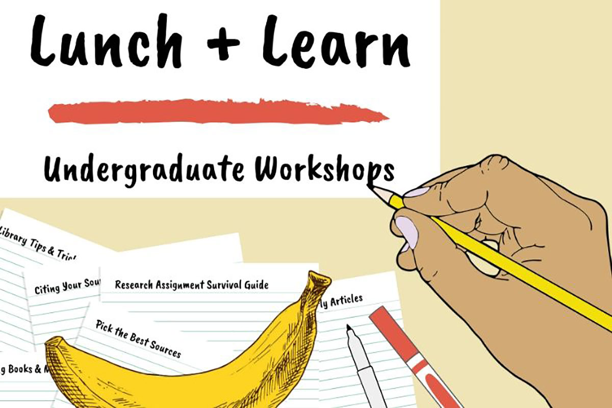 A hand writing with a pencil next to paper, pens, and a banana