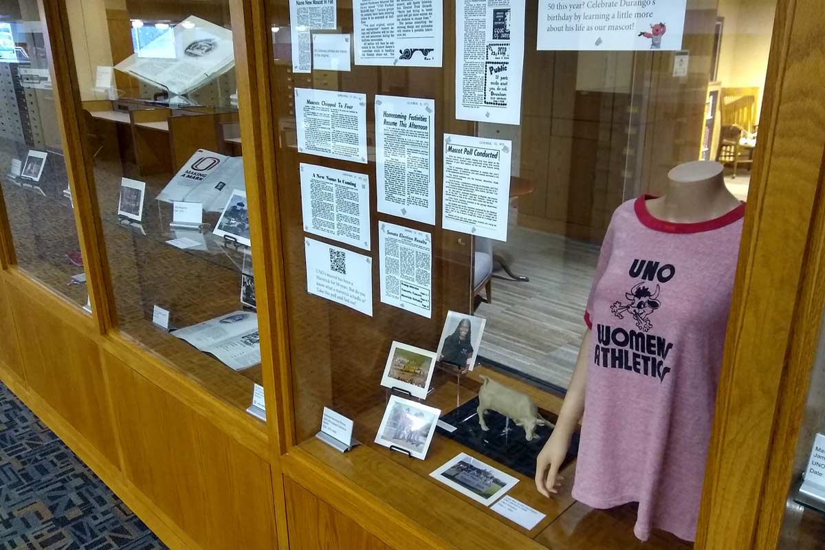 glass and wood display cases with newspaper clippings, tshirt, and memorabilia