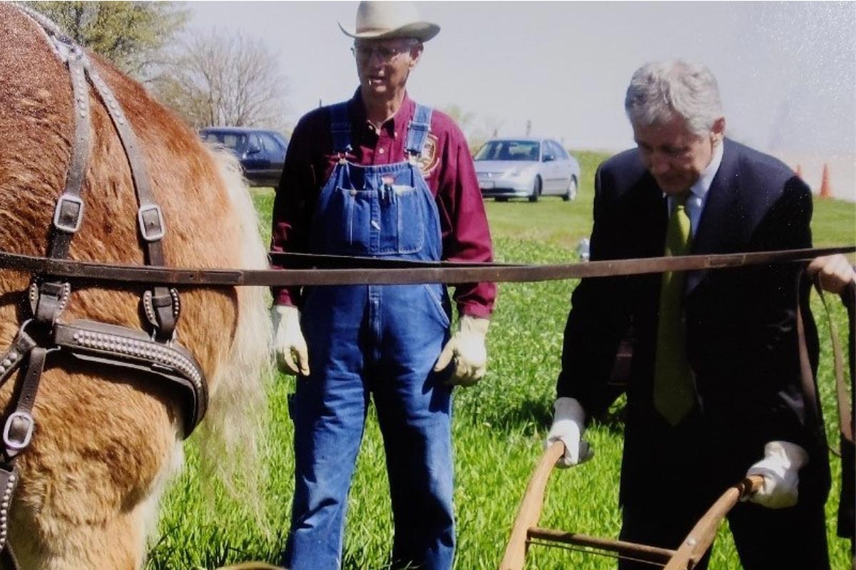 two men by a horse with old farming equipment 