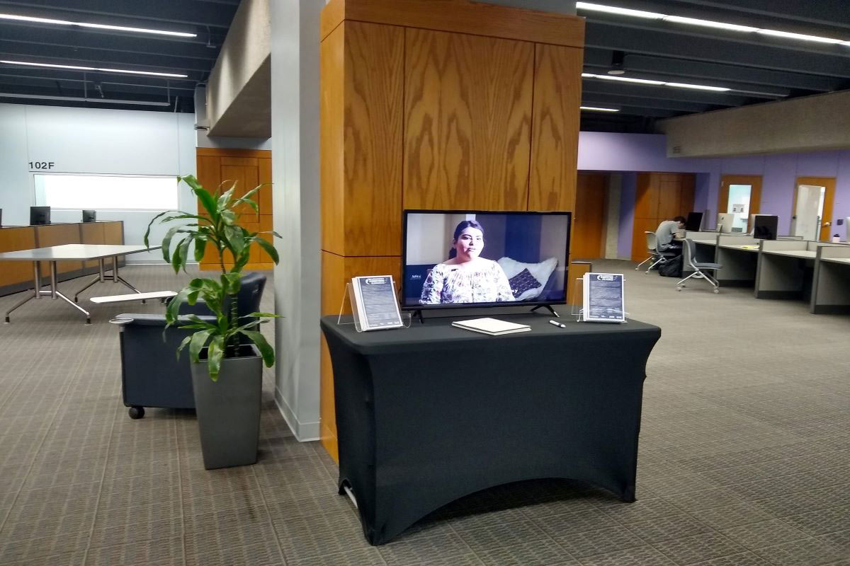 table near a wooden wall with a television on it displaying a Hispanic woman talking