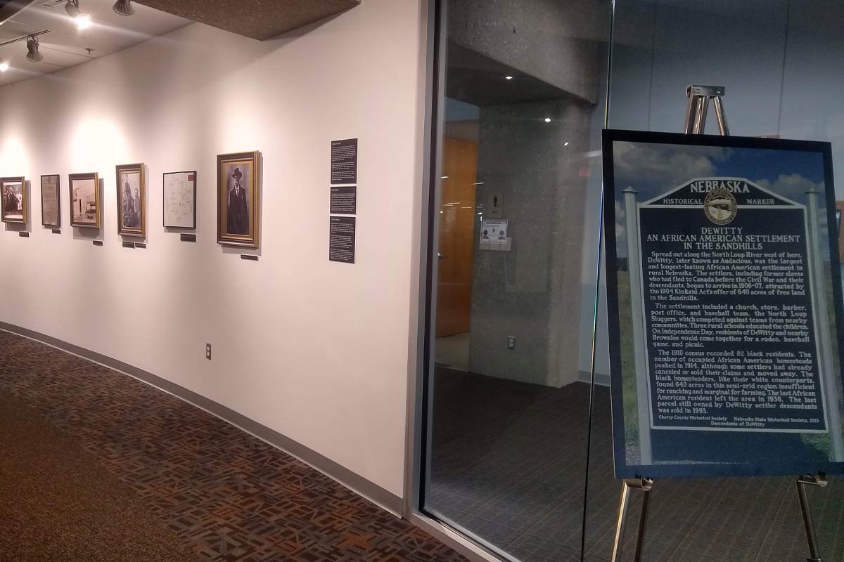 art gallery with photos on the walls and a stand and sign describing the exhibit 