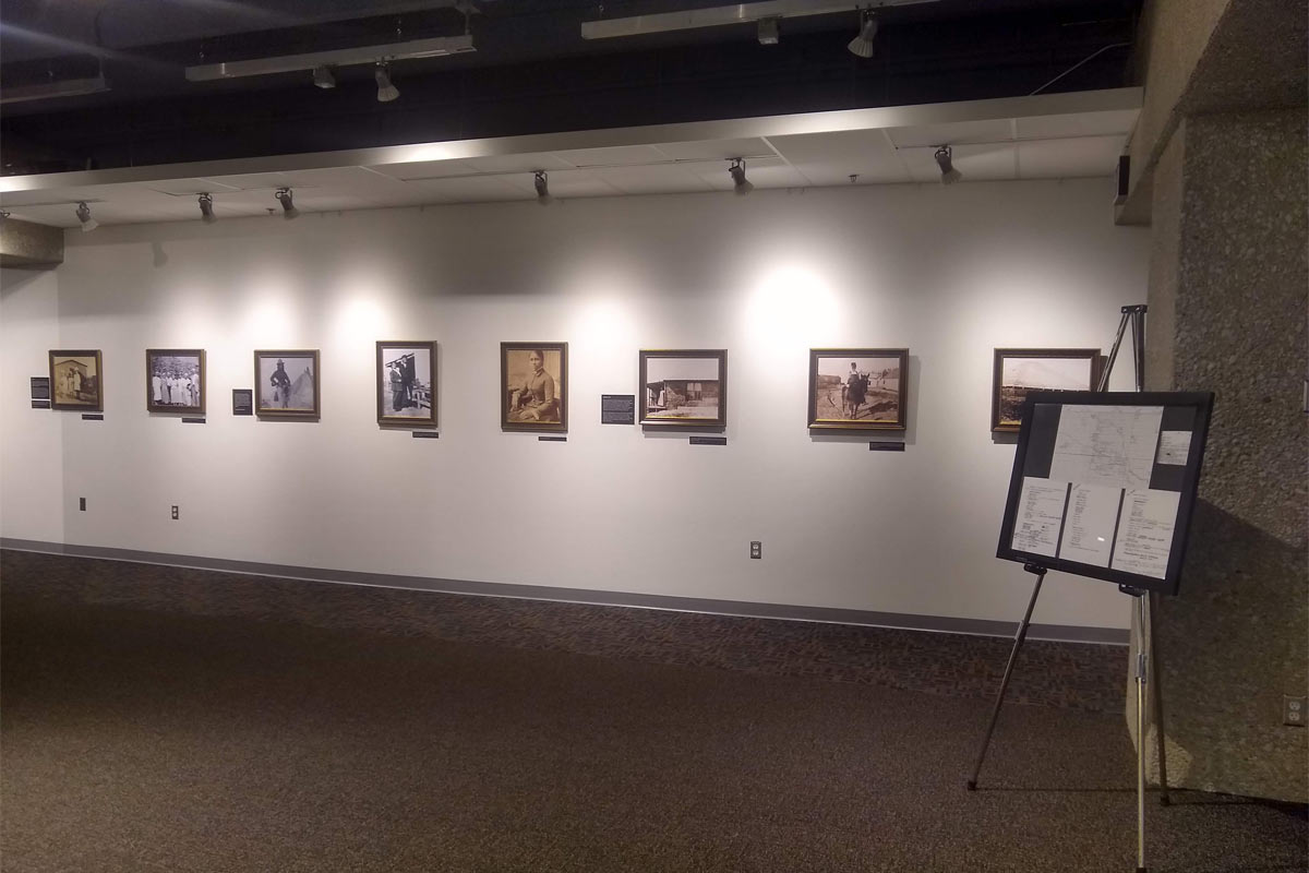 art gallery with photos on the walls and a stand and sign describing the exhibit 