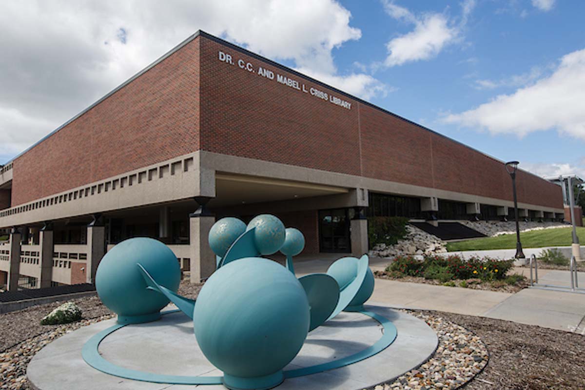 library building in the far ground, with a blue, multi-sphere sculpture in the forefront 