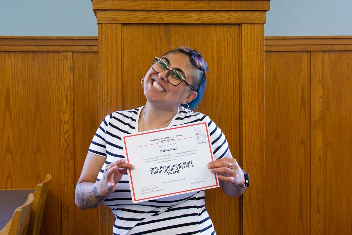 Marina holding a certificate and smiling at the camera 