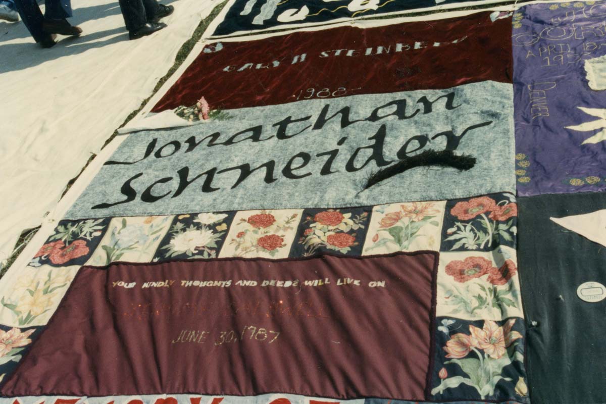 Close-ups of panels from the NAMES Project AIDS Quilt; the name Jonathan Schneider is seen on one of the close patches 