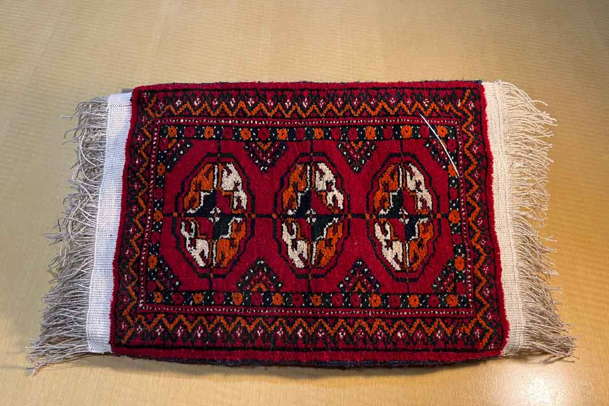 a hand knotted rug in a wooden and glass display shelf