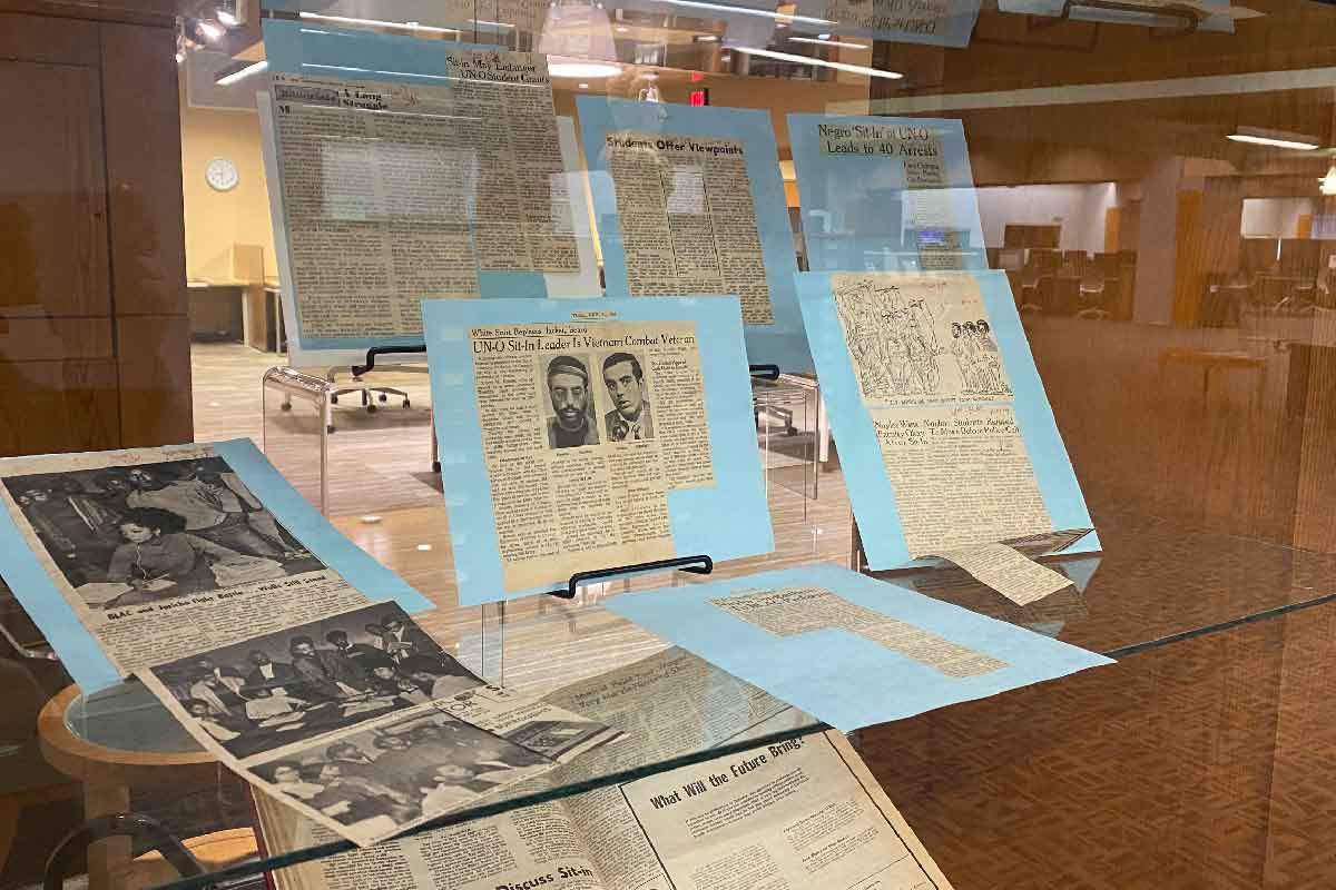 wooden and glass display cabinets with newspaper clippings, old photos, and old papers 