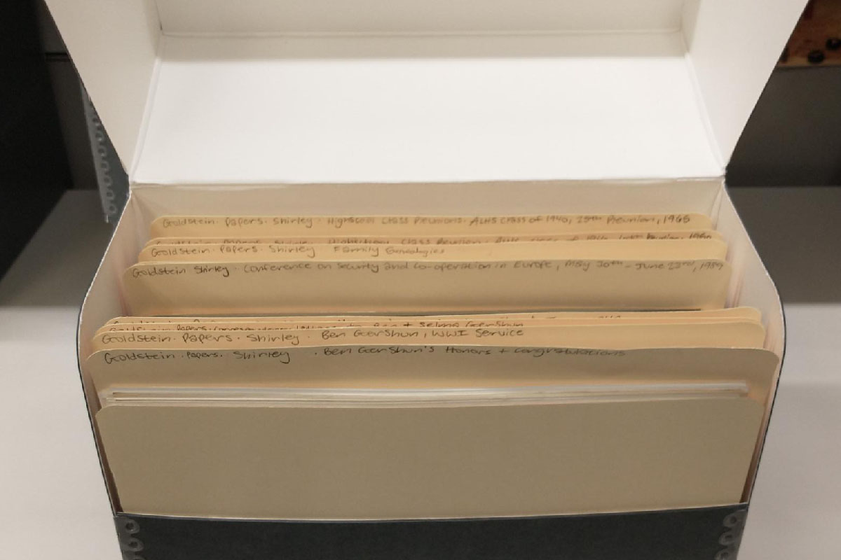 an archival storage box open with rows of manila folders in it