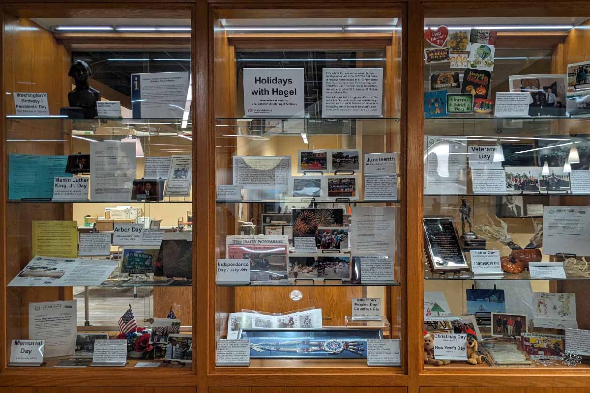 wooden and glass shelves with books, papers, and other items about Chuck Hagel during various holidays