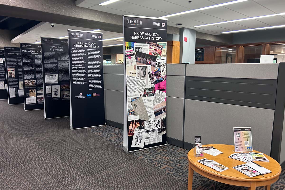 5 black, stand up banners about various LGBTQIA+ topics within the scope of Nebraska. The banners are lined up next to a small grey wall.