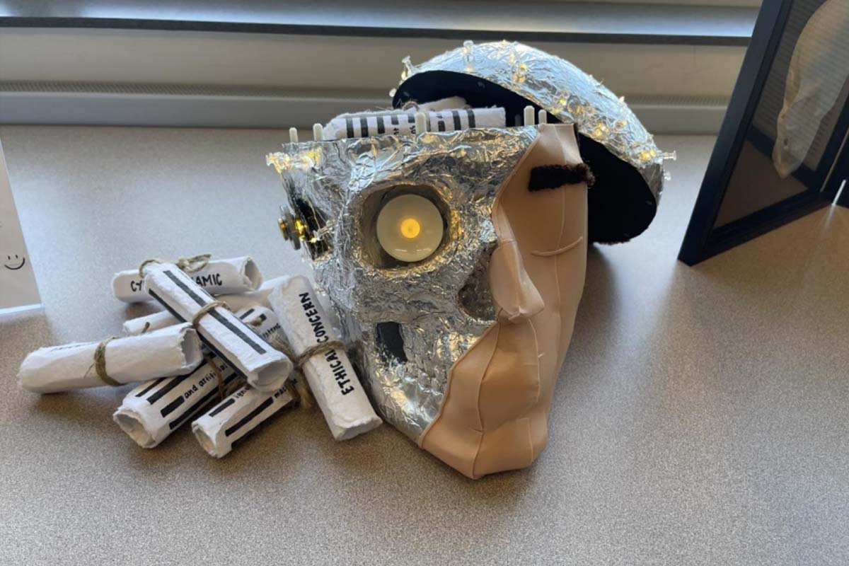 A 3D print of a a half-human, half-robotic face, with rolled-up papers nearby.