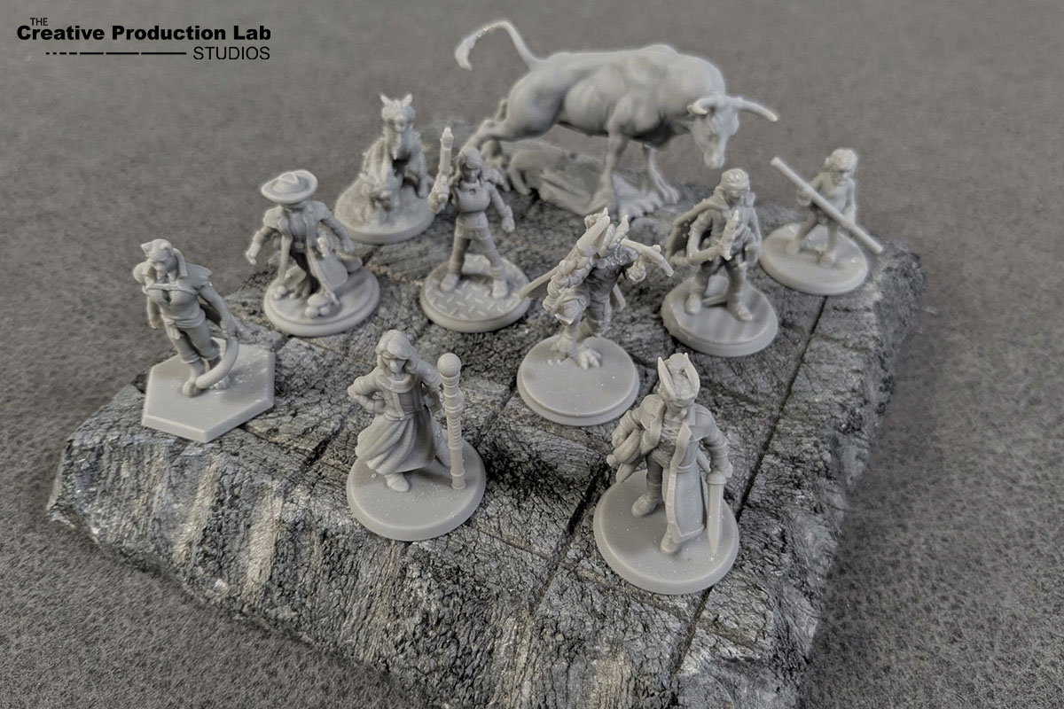 Unpainted gray miniatures arranged on a textured rock-like surface.