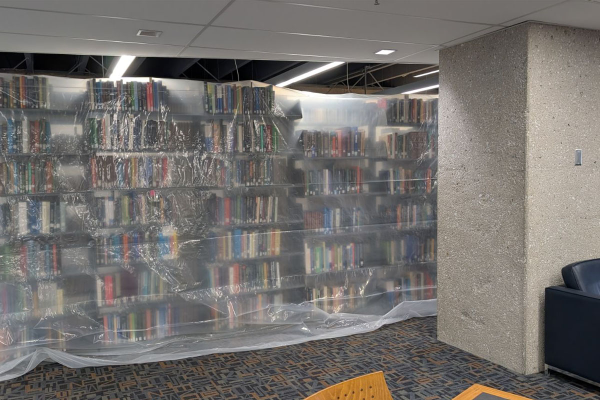 Stacks of books in a library. The stacks are covered by a sheet of plastic.