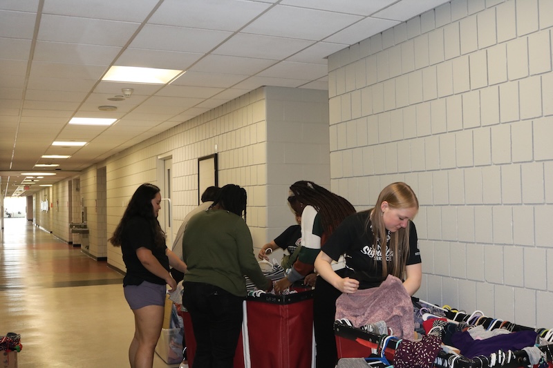 students stand in the hallway of H&K packing up clothing items 