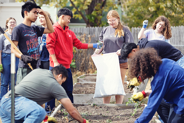 Students work together to plant and weed a community garden.