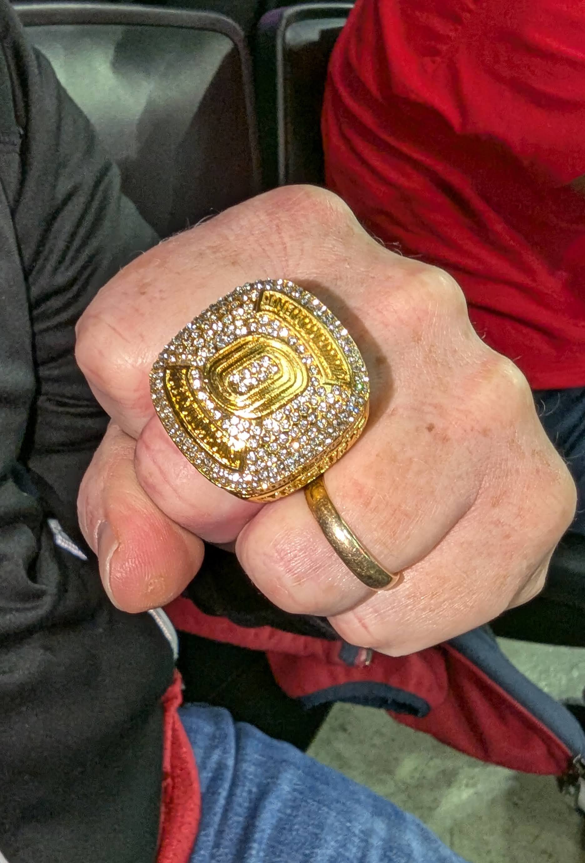 Hand of a UNO Basketball fan wearing a large commemorative gold ring 