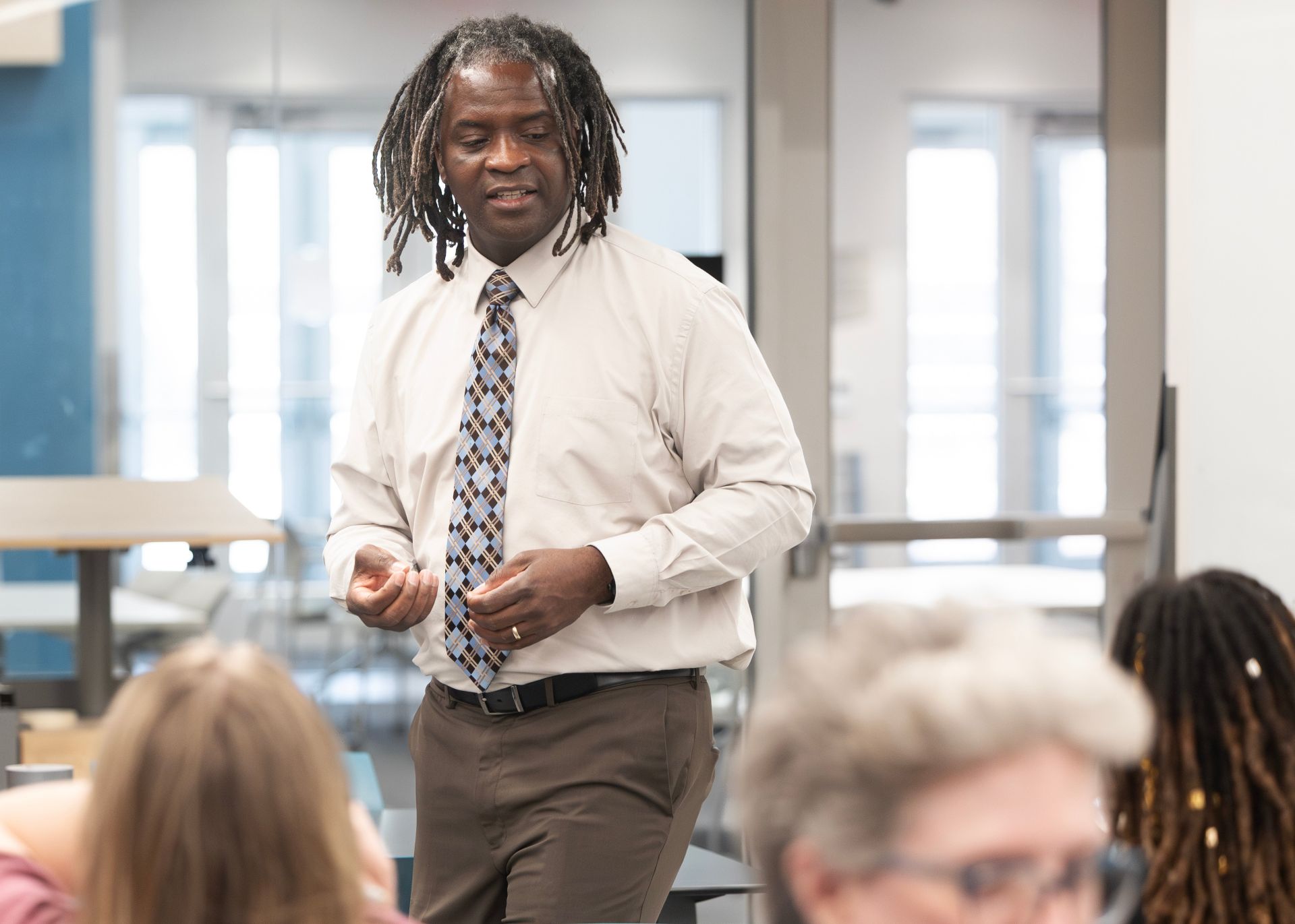 A faculty member speaks to a group of attendees during a classroom discussion.