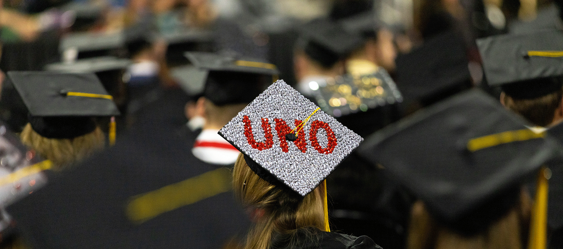 a view of graduating students' mortar boards, with "uno" promptly displayed on top of one in sparkly gems