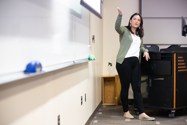 a woman instructor points to a chalkboard during class