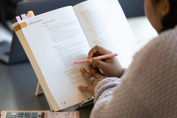 a student highlights text in a book