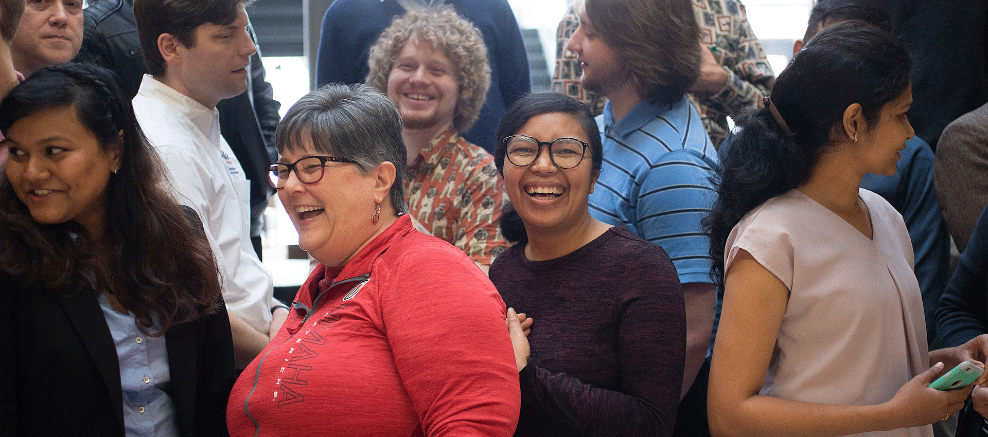 a diverse group of people stand in a crowd smiling