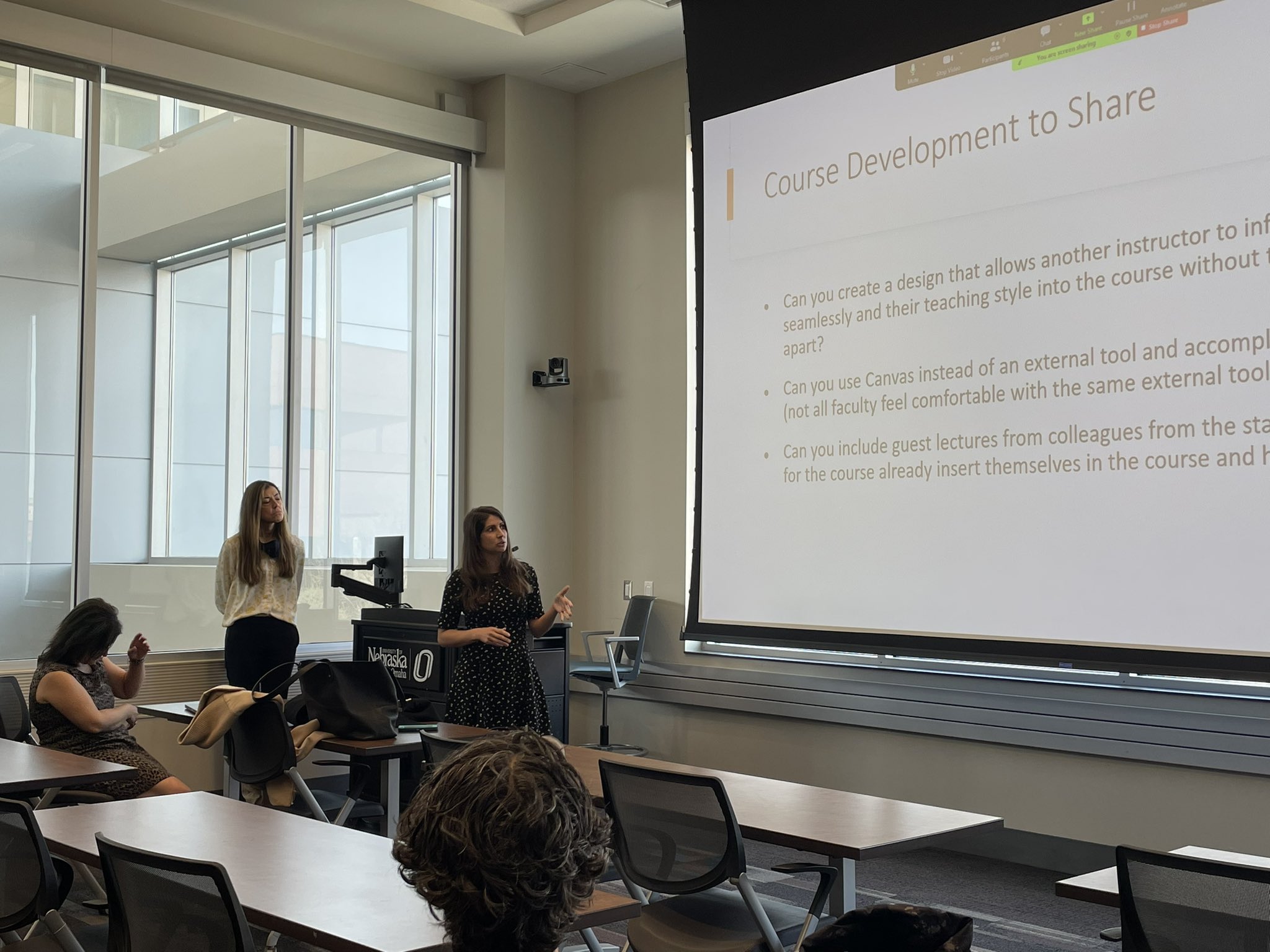 Students sitting at desk, listening to a presentation given by faculty members.