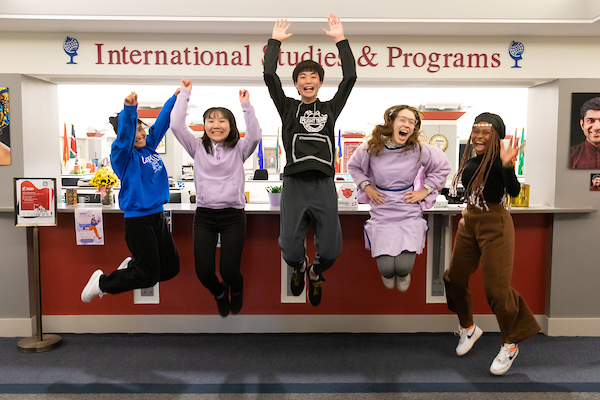 International students in the IP office smile and jump in the air