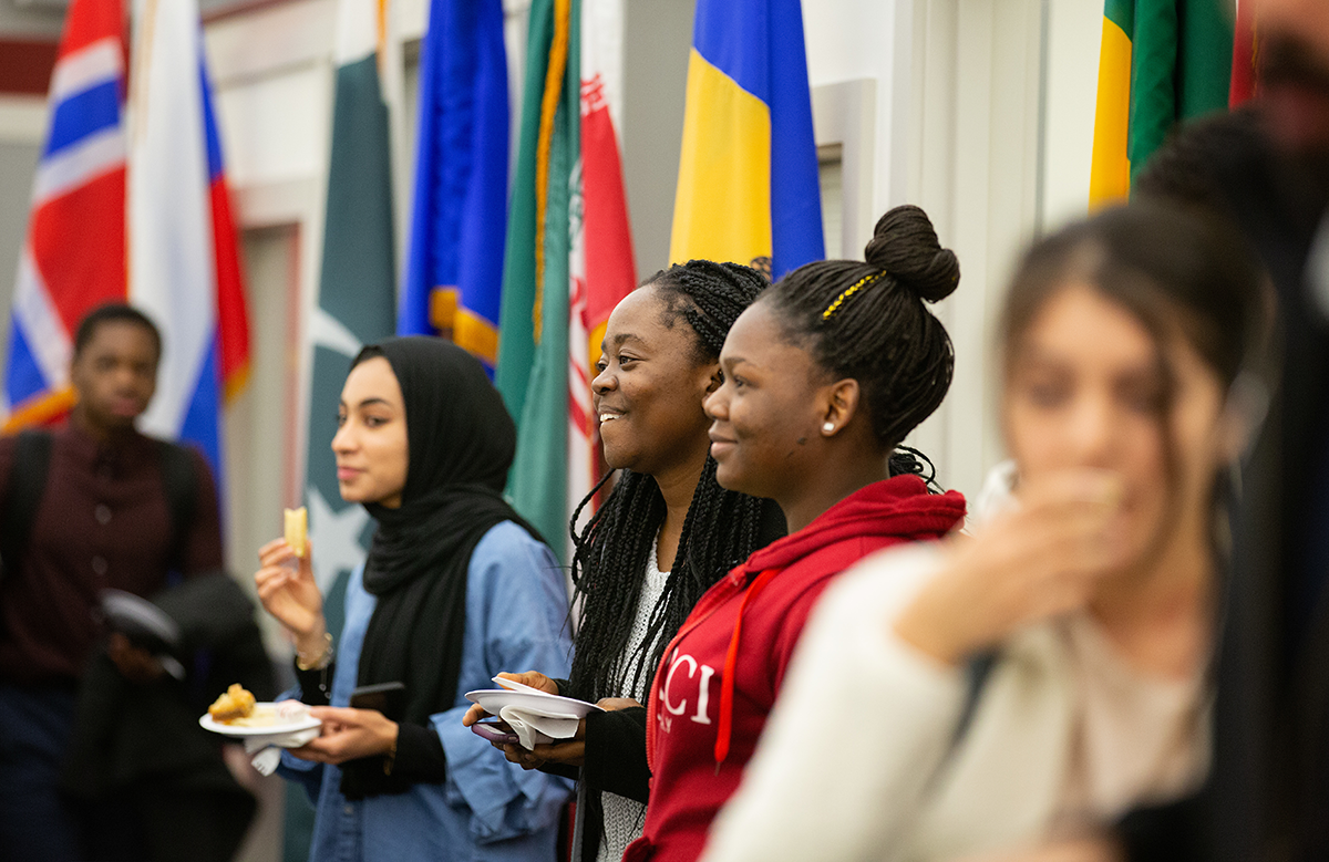 students snack on appetizers in front of a wall of flags in the International Programs Office at UNO.