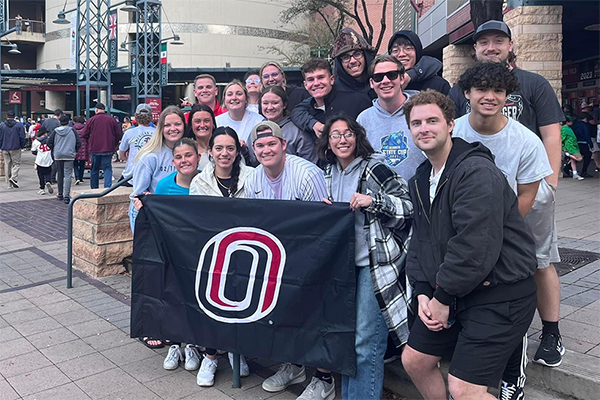 uno stdents stand in a group holding a uno flag