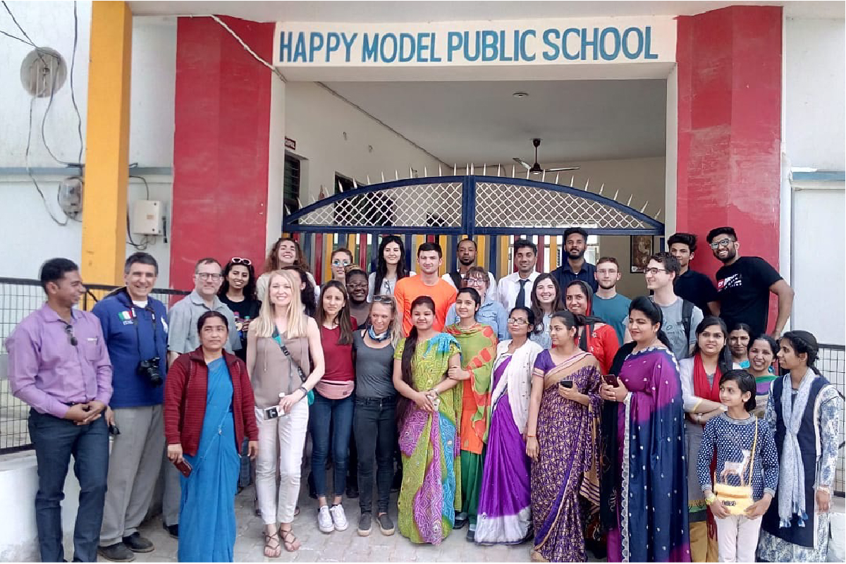 Business & Social Action in India students stand with their Indian peers outside of a school. 