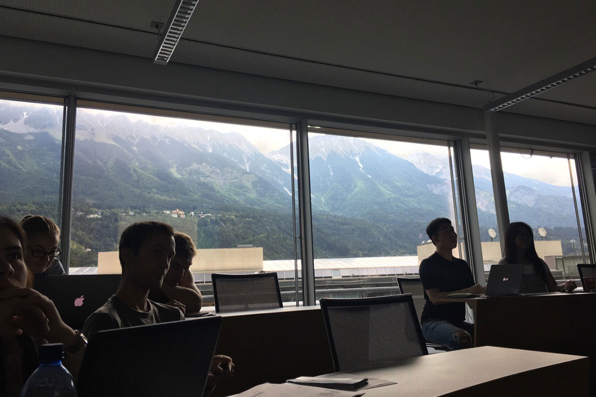 Students sit in a classroom at Management Center Innsbruck, with mountains in the background through the windows