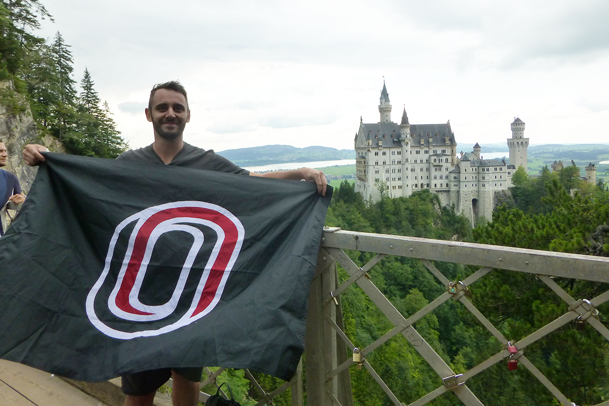Michael Blakely holds the UNO flag in front of Neuschwanstein Castle in Germany