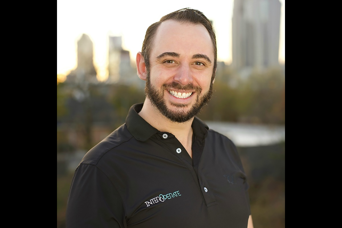 Michael Blakely wearing an InterOperate company polo in front of a cityscape