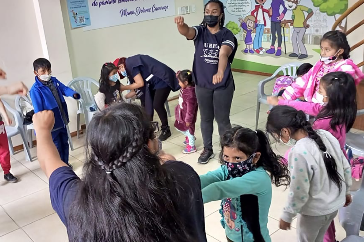 Teachers and students stand in a classroom doing a physical learning activity